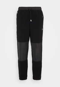Schwarze Fleece-Jogginghose mit strukturiertem Körper, glatten Einsätzen, elastischem Bund mit Kordelzug und einem kleinen Logo-Akzent.