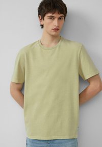 Hellgrünes Baumwoll-T-Shirt mit Rundhalsausschnitt, kurzen Ärmeln und geradem Schnitt. Verfügt über ein kleines Etikett am Saum.