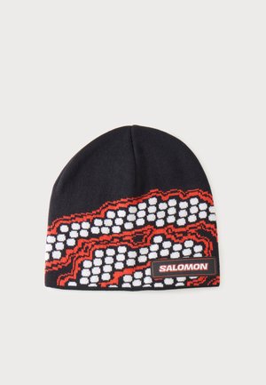Bonnet en tricot noir avec motif pixélisé blanc et rouge et étiquette de marque Salomon sur le bord inférieur avant.