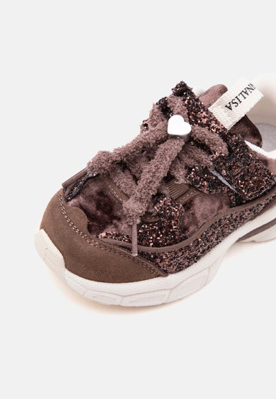 Basket marron pour enfants avec des lacets duveteux, des détails latéraux scintillants, une semelle blanche et un charm en forme de cœur sur les lacets.