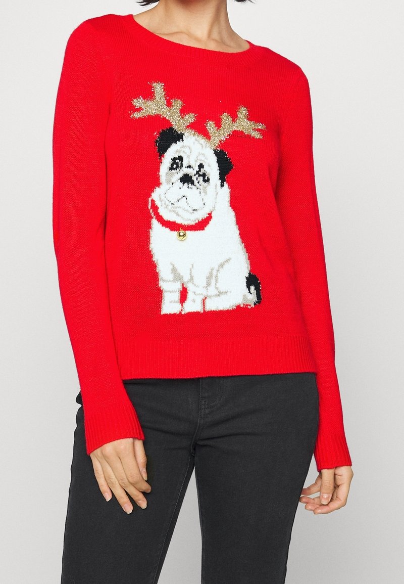 Pull rouge à manches longues avec un motif de carlin portant des bois de cerf et un collier avec une clochette, affichant une texture tricotée et des couleurs vives.