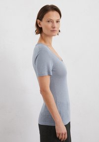 T-shirt azzurro chiaro a maniche corte con scollatura a V profonda, realizzato in tessuto morbido, silhouette aderente che esalta la forma, cuciture minime.
