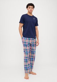 T-shirt de algodão azul-marinho com um pequeno logótipo, combinado com calças de pijama de algodão em padrão xadrez multicolorido nas cores azul, verde, rosa e amarelo.