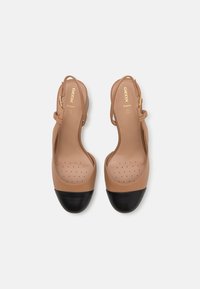 Sandales à talons en cuir couleur tan avec embout noir. Dotées d'une semelle intérieure perforée et d'une bride de cheville ajustable. Marquage doré sur la semelle intérieure.