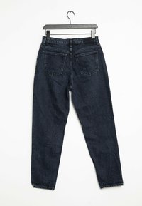 Jeans de mezclilla azul oscuro exhibidos colgados, con un corte recto, cinco bolsillos y un diseño de cinturilla clásico.