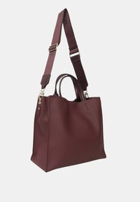 Sac fourre-tout en cuir bourgogne avec double poignée et bandoulière réglable. Fini texturé avec un design minimaliste et des accents en métal.