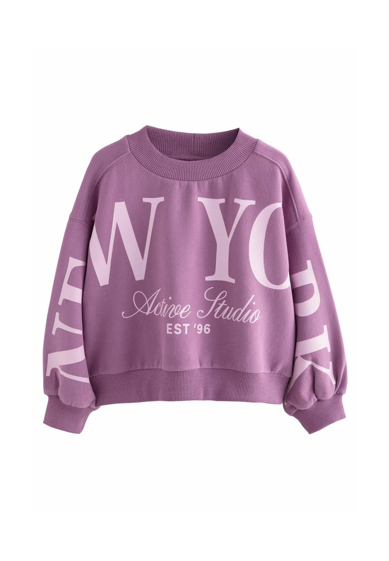 Sweat-shirt court violet avec un grand texte rose pâle "NEW YORK", "Active Studio" et "EST '96", poignets et ourlet côtelés, et col rond.