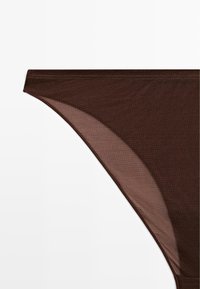 Brune gennemsigtige trusser med en glat tekstur, der har et højskåret design og flade sømme. Subtil glans er tydelig i stoffet.