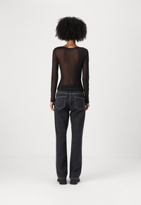 Black sheer long-sleeve top paired with dark denim jeans. The top has a rounded neckline, while the jeans feature classic back pockets and a straight cut.