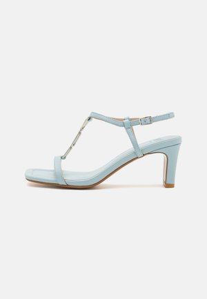 Sandale à talon haut avec bride de cheville bleu clair, au design à bout carré, mettant en avant un accent métallique et une texture en cuir lisse et épurée.