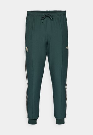 Mørkegrønne sportbukser med elastisk talje, snoretræk og hvide sidelister. Har et logo på låret og ribbede manchetter.