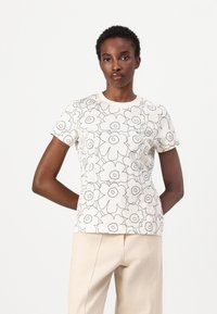 Kortermet, hvit bomulls t-skjorte med et svart blomsterdesign, rund halslinning og avslappet passform. Stilfullt kombinert med beige bukser.