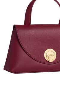 Borsa a mano in pelle rossa con una trama liscia, pattina arrotondata e una chiusura circolare dorata. Presenta due robusti manici superiori per un facile trasporto.