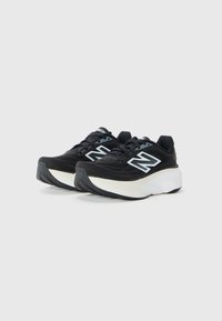 Pair of black and white New Balance running shoes with thick soles, mesh uppers, and white "N" logos on the sides.