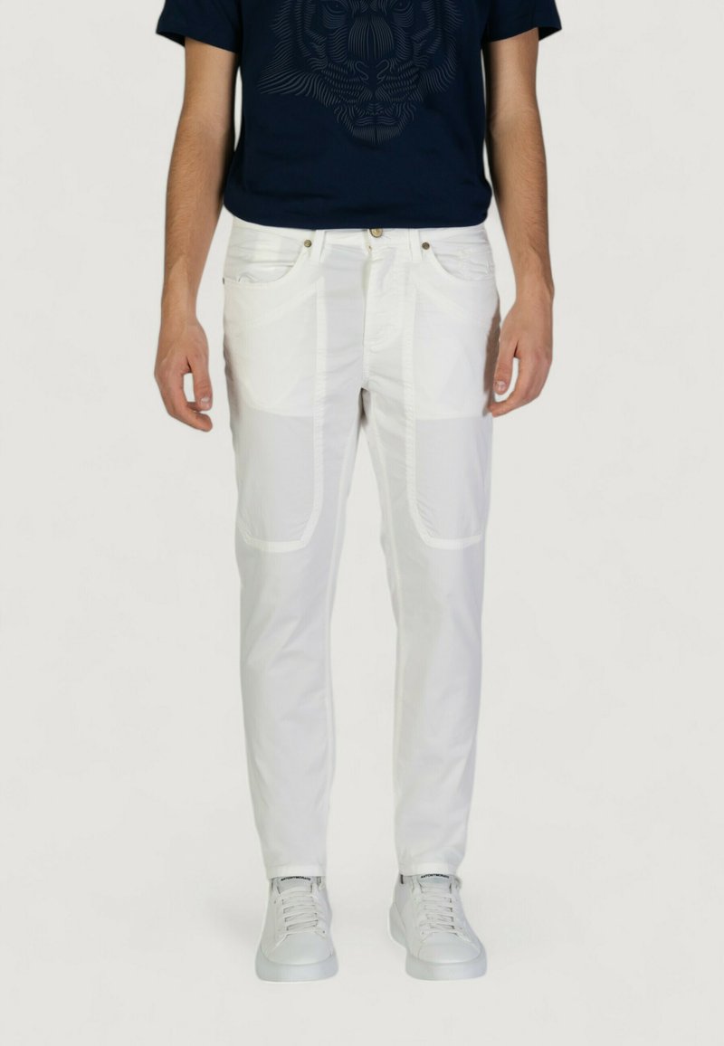 Pantaloni bianchi a taglio slim, con tasche laterali e cuciture in vista. Abbinati a una maglietta blu navy e sneaker bianche.