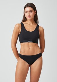 Ensemble bralette et culotte en coton noir avec un décolleté en scoop, une bande logo et une texture lisse. Design simple et classique.