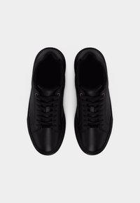 Ζευγάρι μαύρα δερμάτινα χαμηλά αθλητικά παπούτσια με μαύρα κορδόνια, απεικονιζόμενα από πάνω σε ουδέτερο φόντο.