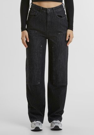Black denim pants with a relaxed fit, featuring large front pockets, visible stitching details, and a high waist design.