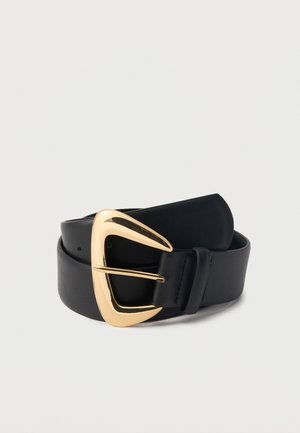 Ceinture en cuir noir enroulée avec une grande boucle triangulaire en or brillant sur un fond gris clair.