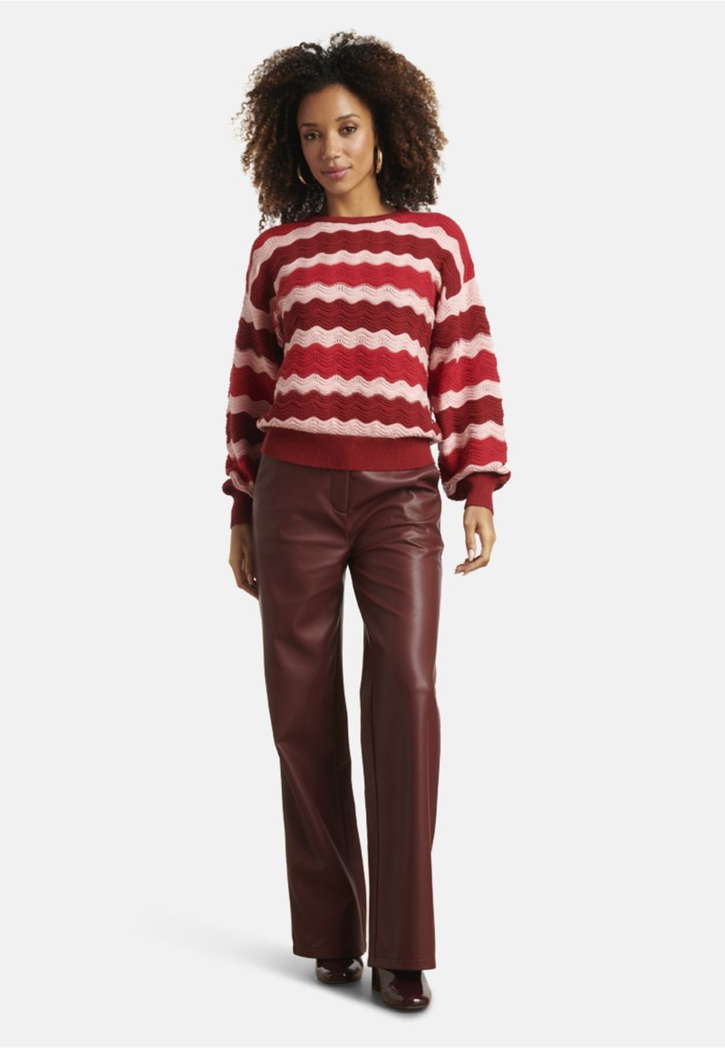 Red and pink striped knitted sweater with wavy texture, paired with burgundy leather pants. Soft, oversized fit with ribbed cuffs.