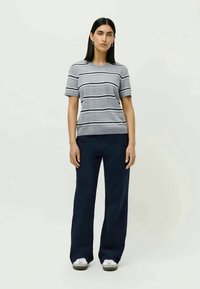 T-shirt rayé gris à manches courtes et col rond, associé à un pantalon large bleu marine. Tissu décontracté avec une coupe ample et sans motifs distincts.