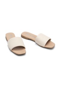 Sandali bianchi a scivolo con una fascia larga, suola piatta e superficie liscia opaca. La parte inferiore è di un colore beige naturale e ha un design minimalista.