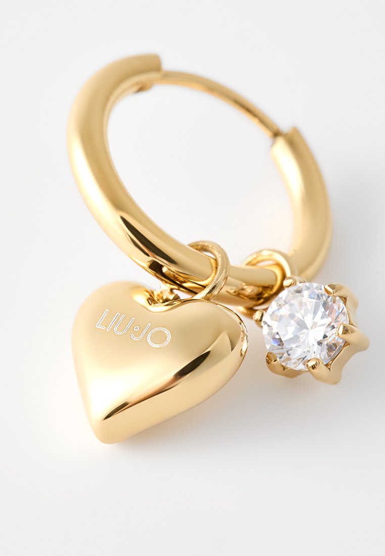 Złoty kolczyk w kształcie obręczy z błyszczącym sercowym zawieszką grawerowaną "LIU·JO" oraz przezroczystym, okrągłym wiszącym kamieniem na białym tle.