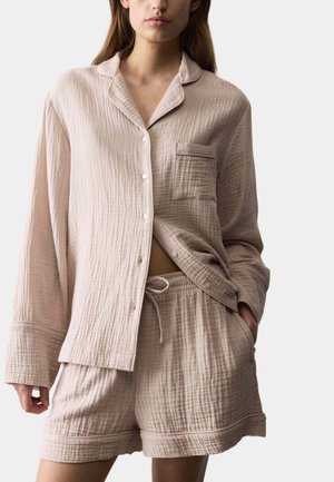 Hellbeiges, strukturiertes Baumwoll-Pyjama-Set mit einem langärmligen Hemd mit Knopfleiste und Tasche sowie passenden Shorts mit elastischem Bund.