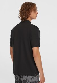 Sort kortærmet polo-shirt med en diskret struktureret overflade, der har lige afslutning og klassisk krave.