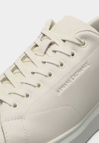 Λευκό χαμηλό αθλητικό παπούτσι με λευκά κορδόνια, ανάγλυφη επωνυμία "ARMANI EXCHANGE" στο πλάι και επάνω μέρος από λείο δέρμα.