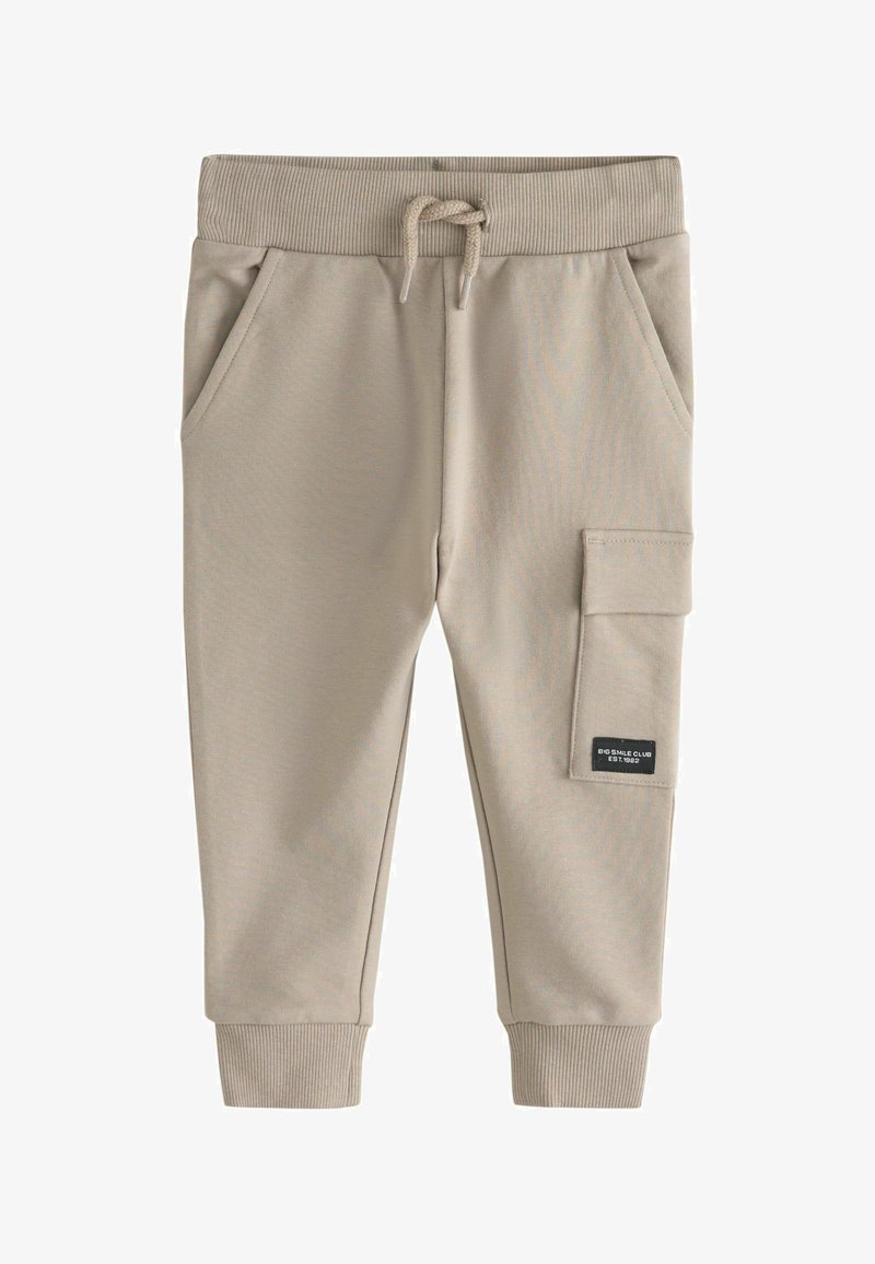 Beżowe dresy z bawełny z prążkowanym pasem w talii i mankietami, z możliwością regulacji sznurkiem, bocznymi kieszeniami oraz kieszonką z naszywką na udzie.