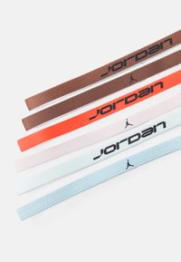 Įvairūs audinio diržai su "Jordan" logotipu, prieinami rudos, oranžinės, rožinės ir šviesiai mėlynos spalvų, su kontrastingomis tekstūromis ir raštais.