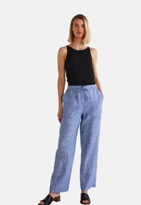 Pantalon en lin bleu clair avec une coupe ample, doté d'une taille à cordon de serrage et de poches latérales, associé à un haut sans manches noir.
