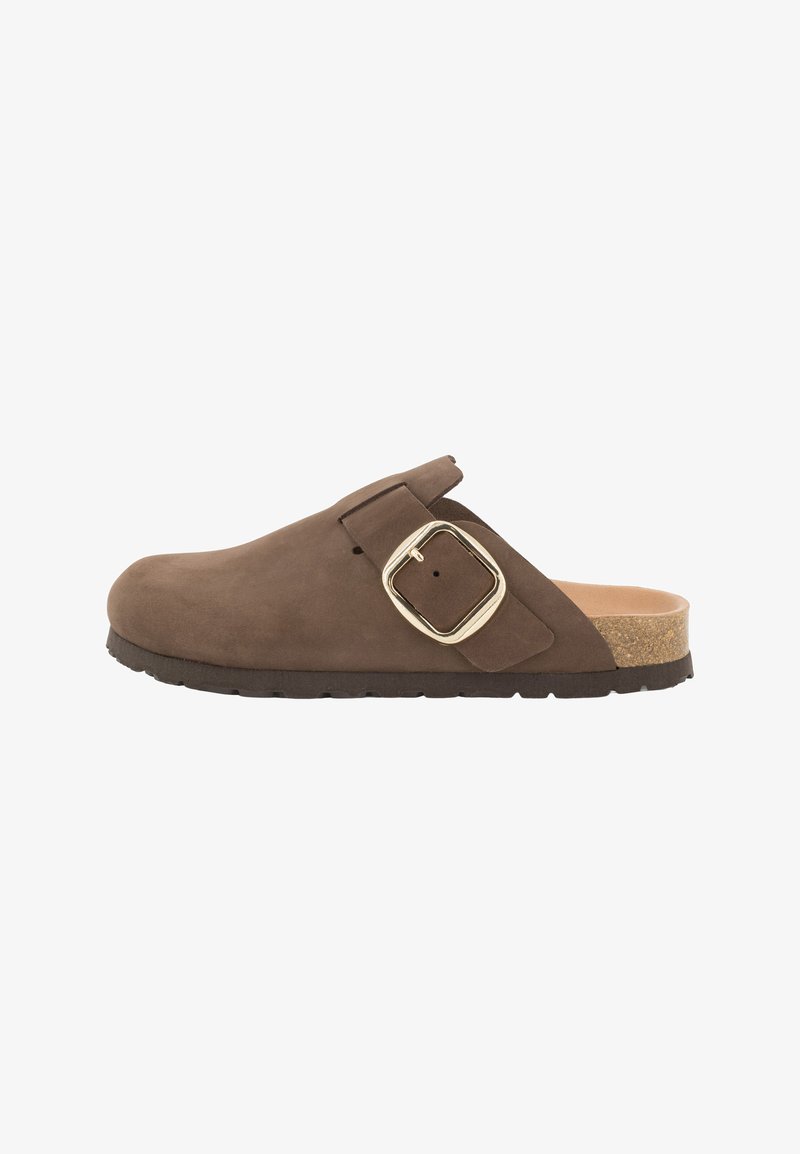 Sabot en daim marron avec une grande boucle dorée et un semelle en liège. Présente un bout arrondi et une semelle en caoutchouc texturée. Design ouvert à l'arrière.
