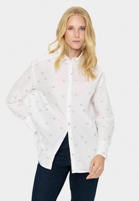 Witte button-up shirt met zwarte geborduurde wolkenvormen, met lange mouwen en een relaxte fit. Combineer met donkere denim jeans.
