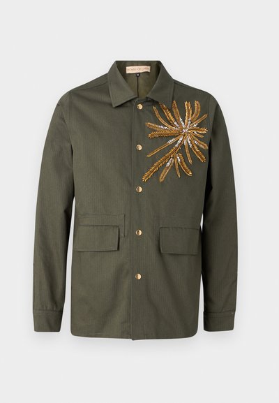 Olive roheline jakk terava kraega, kuld- ja hõbeämbroideritud lehekujundusega vasakul ning kahe esisegi taskuga nupuga sulgemiseks.