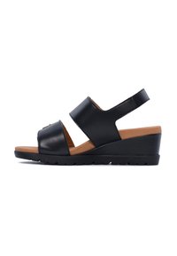 Le sandali con tacco a cuneo neri presentano ampie fasce in pelle liscia, una soletta color tan e una suola in gomma testurizzata per una migliore aderenza.