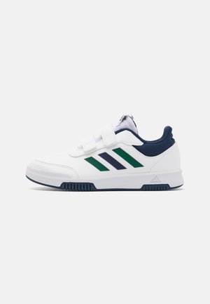 White athletic shoes with green and navy stripes, velcro straps, a textured finish, and a rubber sole for traction.