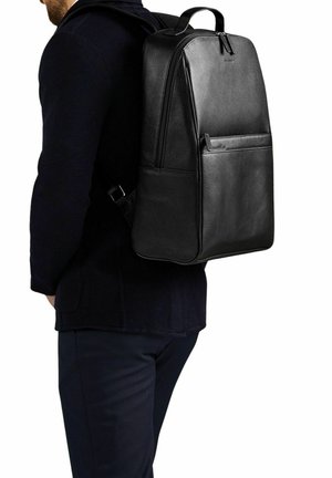 Svart läderryggsäck med en strömlinjeformad design, med ett zip-lock huvudfack och en framficka. Justerbara remmar och bärhandtag ingår.