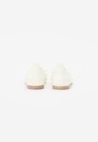 Hvite lær sko med lav profil, med et teksturert design, rund t�å og beige gummisåle. Snøring er knyttet foran.