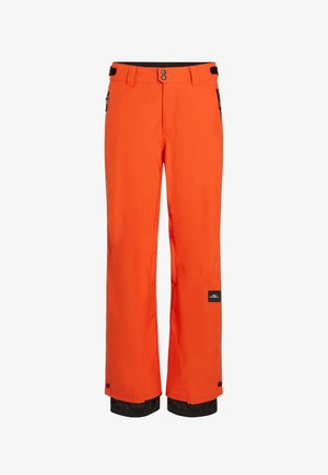 Jasne oranžové lyžiarske nohavice vyrobené z odolného materiálu, s čiernym pásom, nastaviteľnými úchytmi a zipsovými vreckami s elastickými manžetami.