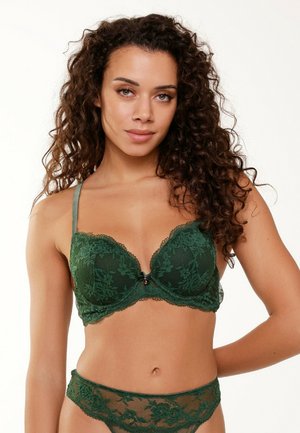 Lace bra in dark green with padded cups, intricate floral patterns, and a small bow at the center; includes matching lace panties.