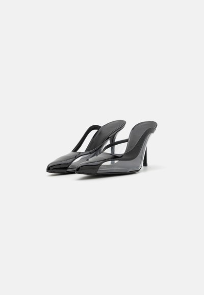 Black patent leather slingback heels with a pointed toe and transparent cutouts. Features a thin stiletto heel and smooth texture.