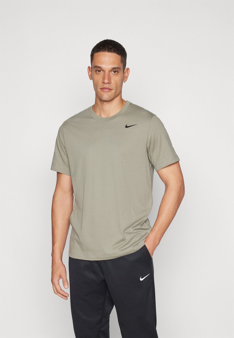 Nike lühikeste varrukatega t-särk oliivrohelises värvitoonis, puuvillane materjal; nurgas must logo ja ümar kaelus, kombineeritud mustade pükstega.