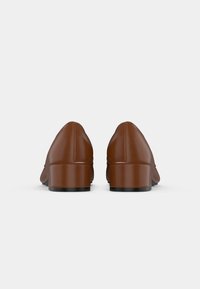 Chaussures en cuir marron avec un bout arrondi, un petit talon carré, une texture lisse et un design minimaliste, sans quincaillerie ou embellissements visibles.