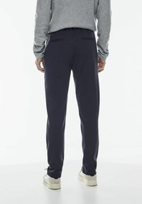 Marina joggingbyxor gjorda av mjukt tyg, med en avslappnad passform, elastisk midja och två bakfickor. Stylad med en grå tröja.