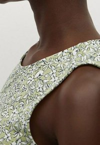 Robe sans manches en tissu vert clair, présentant un motif floral en noir et blanc ; texture lisse, encolure ronde, coupe ajustée.