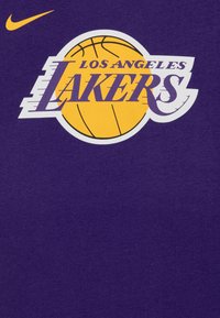 Fialové bavlněné tričko s bílým a žlutým logem "Los Angeles Lakers" a grafikou basketbalového míče, s oranžovým logem Nike.