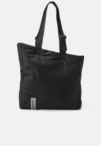 Borsa tote nera in nylon con cuciture rinforzate, due manici robusti e una piccola etichetta grigia sul lato. Texture liscia, forma rettangolare.