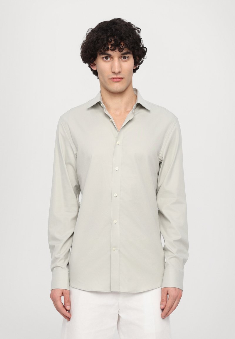 Camisă butonată de culoare gri deschis, cu mâneci lungi, guler și o textură netedă. Prezintă o croială standard și butoane albe pe placket.